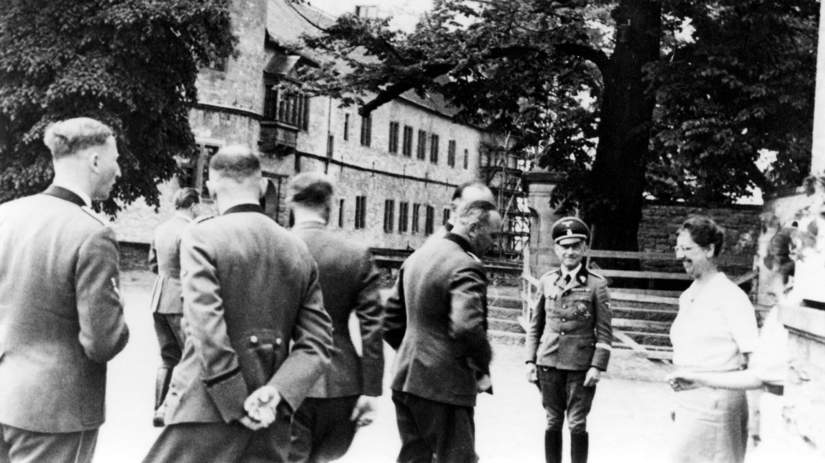 Gruppenführertreffen auf der Wewelsburg, Mitte Juni 1941 - Im Hintergrund ist die Ostfassade der Burg zu erkennen. Burghauptmann Siegfried Taubert (mit Schirmmütze) blickt Richtung Kamera. Reinhard Heydrich ist am linken Rand zu erkennen, die Leiterin der Hauswirtschaft der Wewelsburg, Elfriede Wippermann, am rechten Rand.